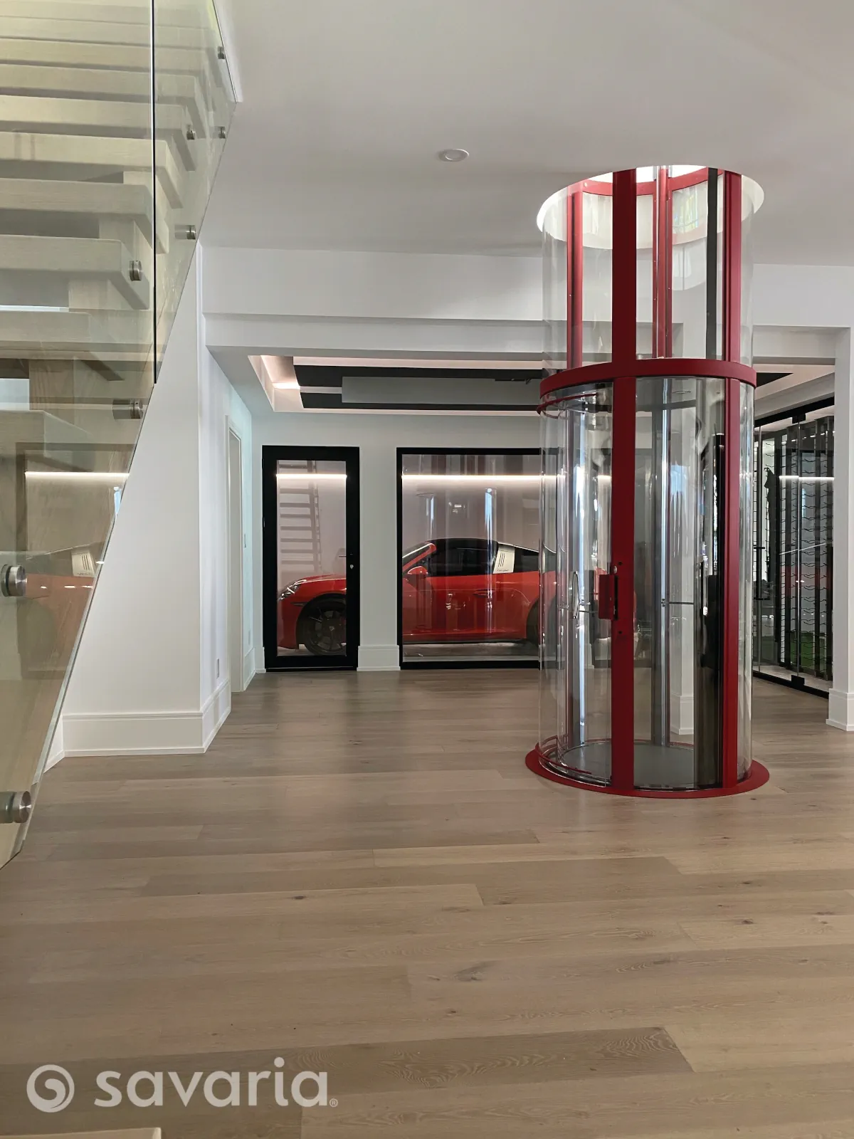 Savaria Vuelift Round glass elevator as centerpiece between dual curved staircases in grand foyer